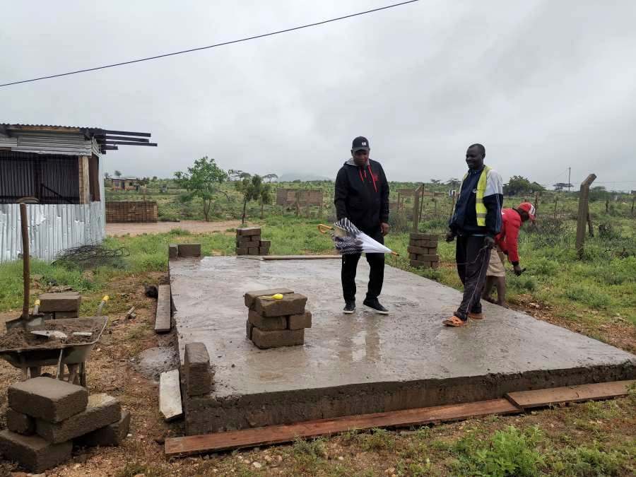 We arrive on a rainy day. The foundation of the chicken house is done. George is inspecting the work of contractor Kennedy and his team. 